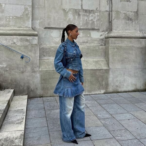 Women in an oversized denim ensemble with her coat cut, pleated skirt, and wide-legged jeans.