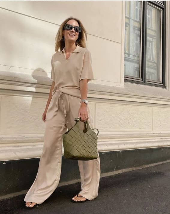 Laid-back summer outfit with ecru polo shirt, satin trousers, and flip-flops.