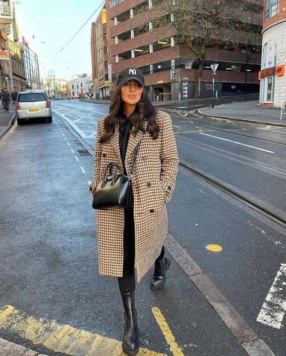 Woman in a houndstooth-patterned coat, black leggings, and chunky Chelsea boots for a street-style winter look.