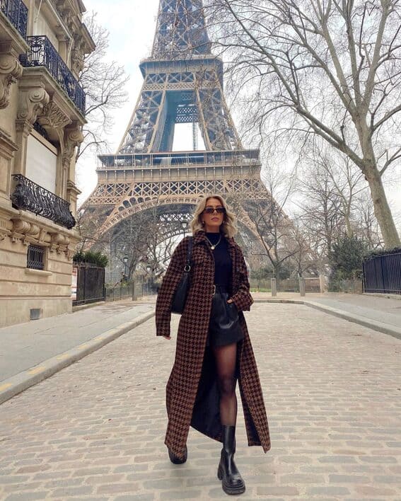 The woman is wearing a fur coat with a houndstooth over a minimal black ensemble for a chic winter look.