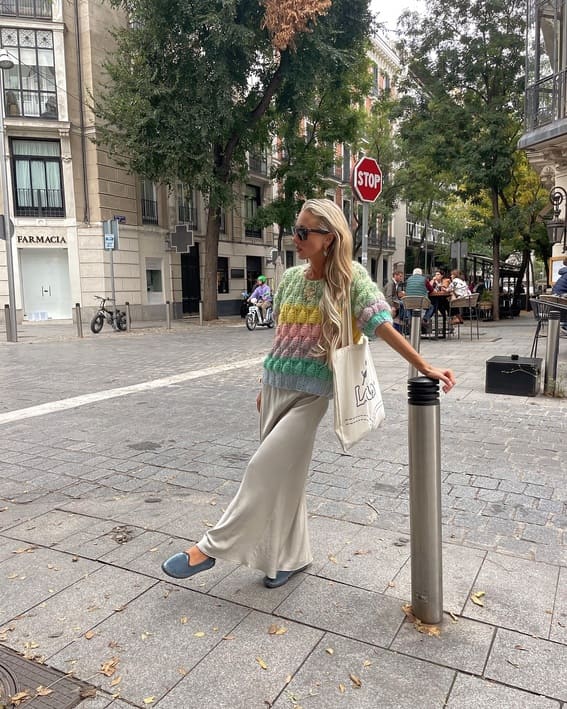 A relaxed street-style outfit that features a pastel-colored knitted sweater, large-leg silk pants, and comfy slippers.