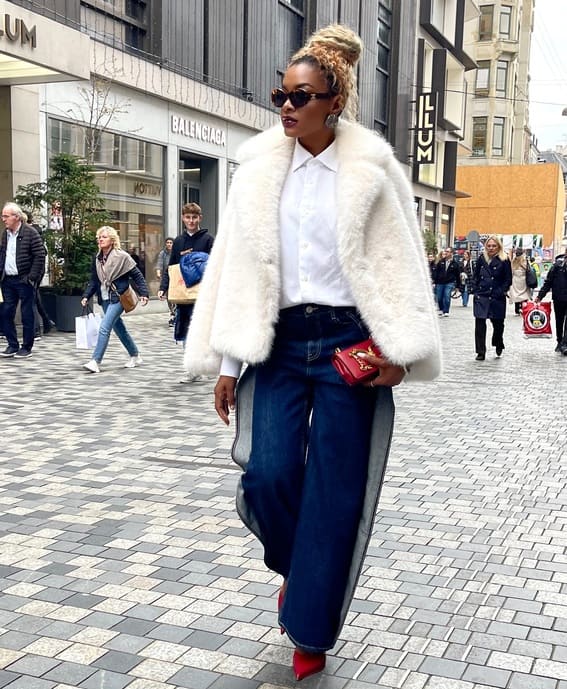 This striking style includes faux fur in white paired with dark wide-leg jeans, red pumps, and a white shirt underneath.