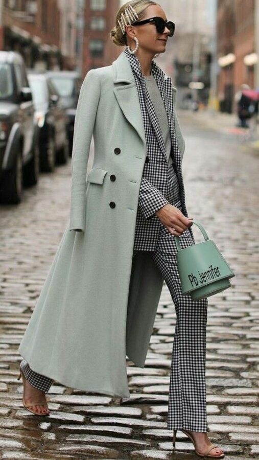 Woman wearing a black and white gingham suit with a mint green trench coat and matching handbag