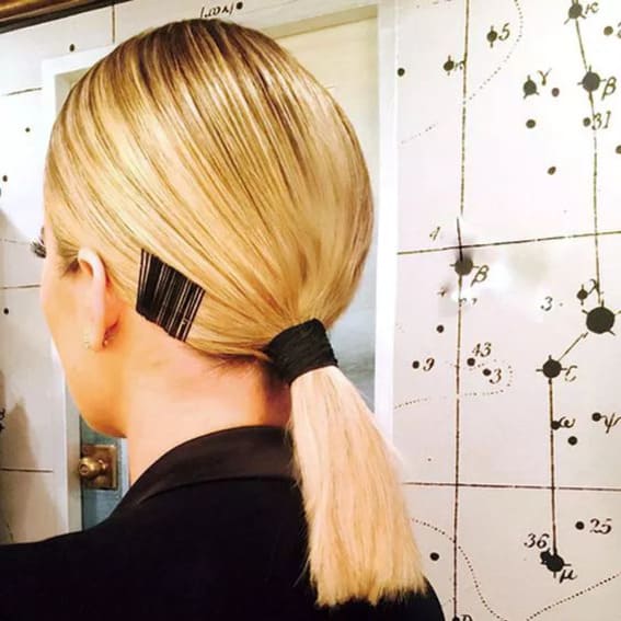 A sleek ponytail that has bobby pins hanging from the side for a fashionable look.