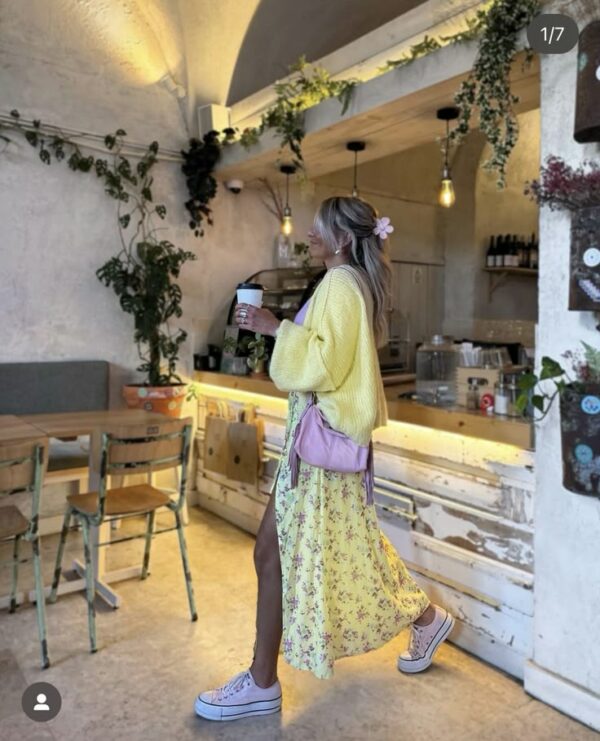 Woman wearing a yellow floral maxi dress, yellow cardigan, pink sneakers, and a pink crossbody bag