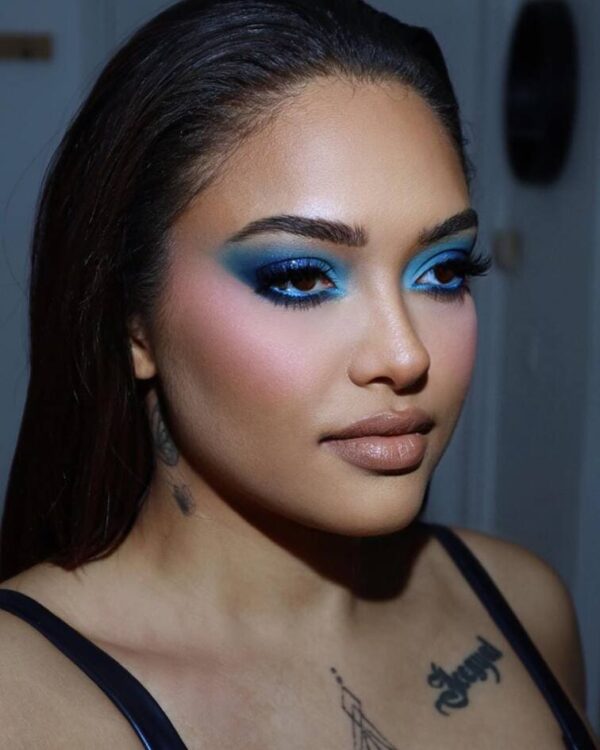 Woman with gradient blue eyeshadow, focusing on smoky tones with soft blush and natural lips.