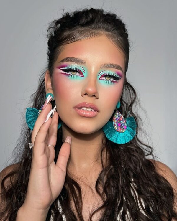 A bold, vibrant look with neon aqua and purple eyeshadow paired with turquoise statement earrings.