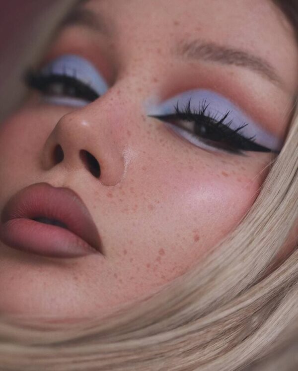 Close-up of a model with bold winged pastel blue eyeshadow and defined black liner.