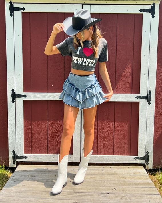 A fun and playful look features a ruffled denim skirt, graphic tee, and white cowboy boots. 