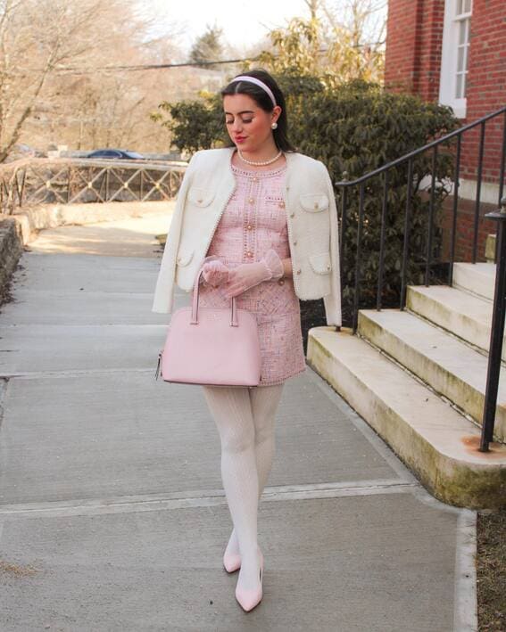 Woman in a pink tweed dress, ivory cropped jacket, and pearls, accessorized with gloves and a blush handbag.