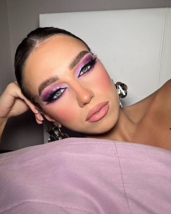 Close-up of glamorous pink and purple eyeshadow with fluttery lashes and defined brows.