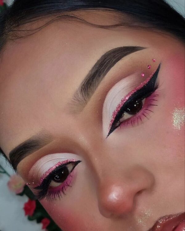 Close-up of a glittery pink cut-crease with rhinestone accents and winged liner.