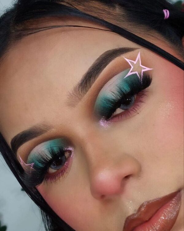 Close-up of vibrant teal and pink eye makeup with a star accent above the brow.