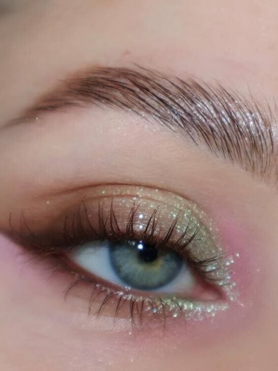 Close-up of subtle green and pink glitter eyeshadow with natural lashes.