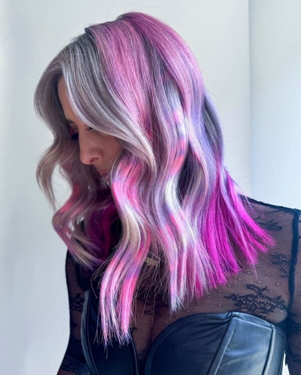 Side view of wavy hair, neon magenta, silver, and lavender tones merging.