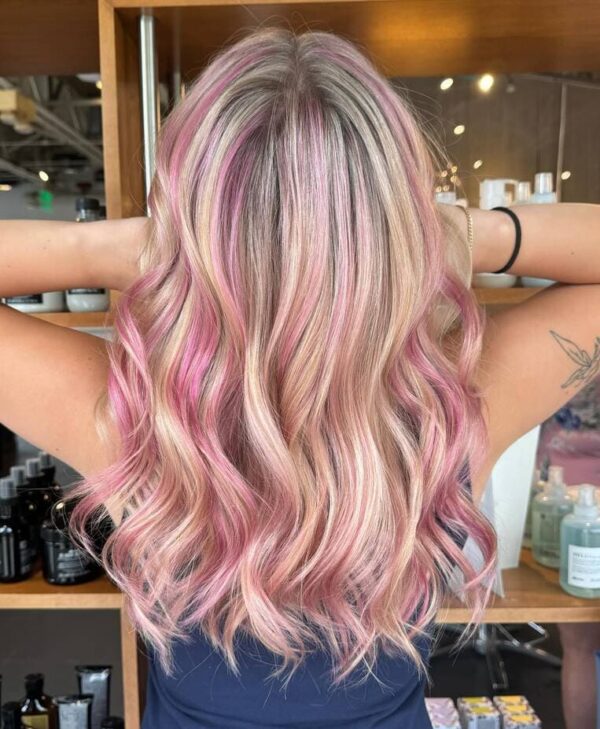 View back of blonde hair, with highlights of pink balayage in soft waves.