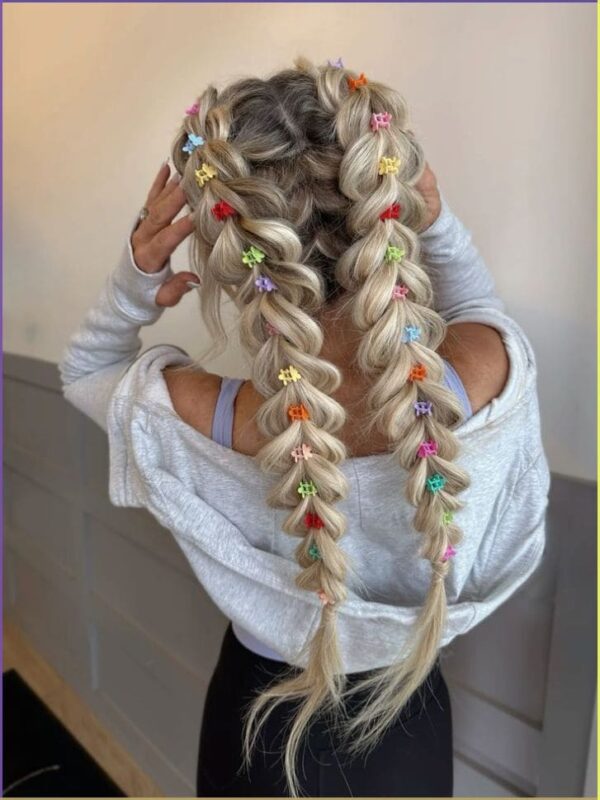 Blonde hair styled into double fishtail braids decorated with colorful mini butterfly clips