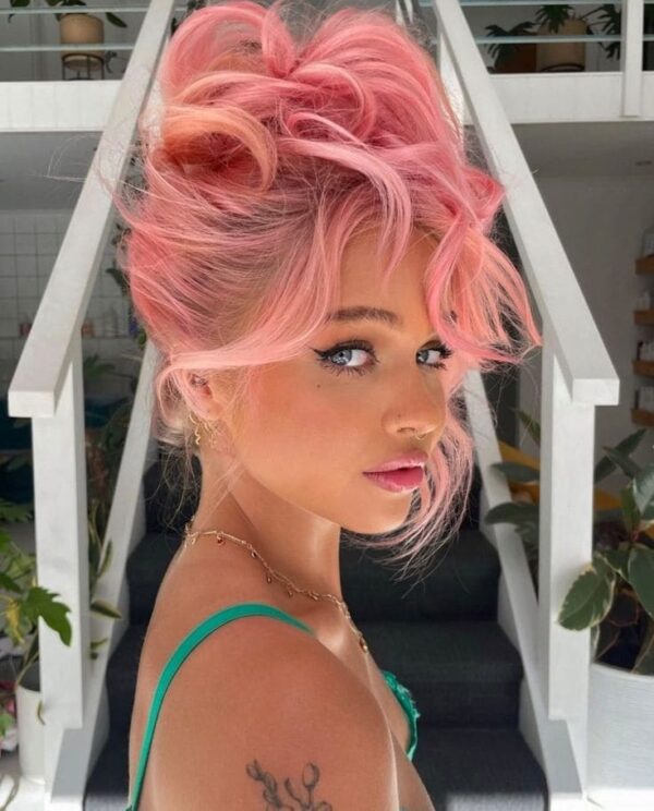 Woman with voluminous pastel pink updo hairstyle and curtain bangs