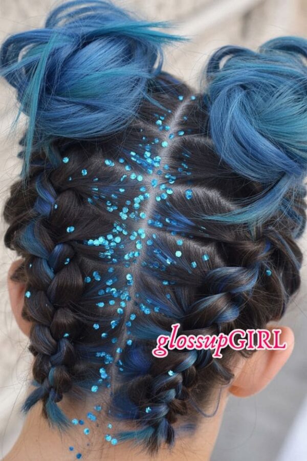 Dark hair with blue highlights styled into space buns, braided sections, and bright blue glitter along the part.