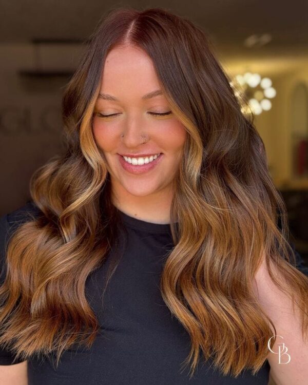 Warm copper balayage with soft waves and face-framing highlights.