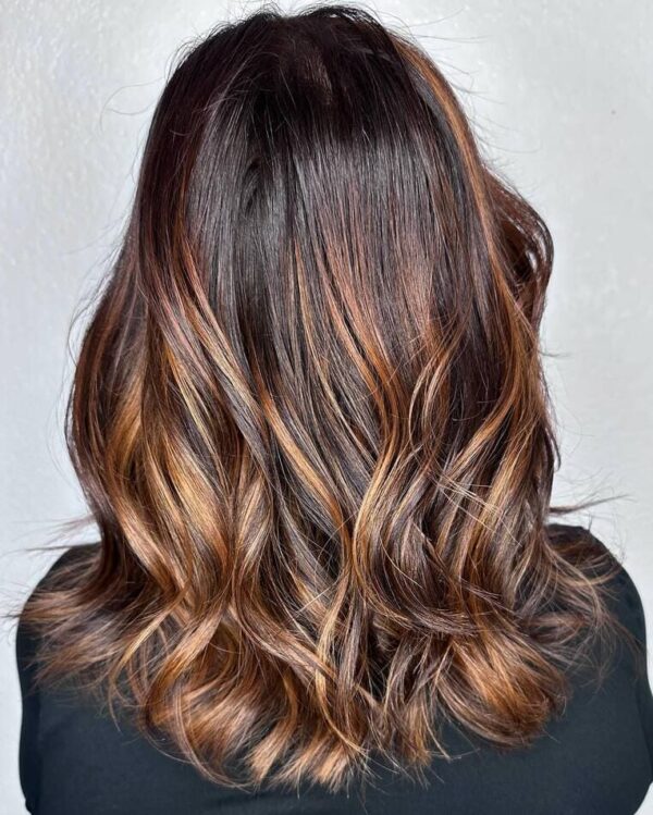 Dark brown hair with auburn and copper streaks in loose waves.