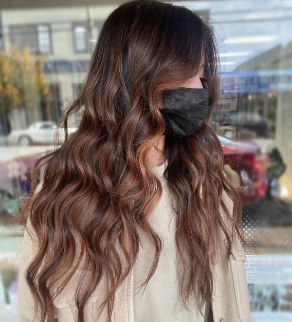 Mid-length wavy hair with caramel copper highlights.