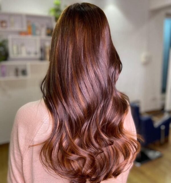 Long, wavy hair with subtle red-toned copper highlights.