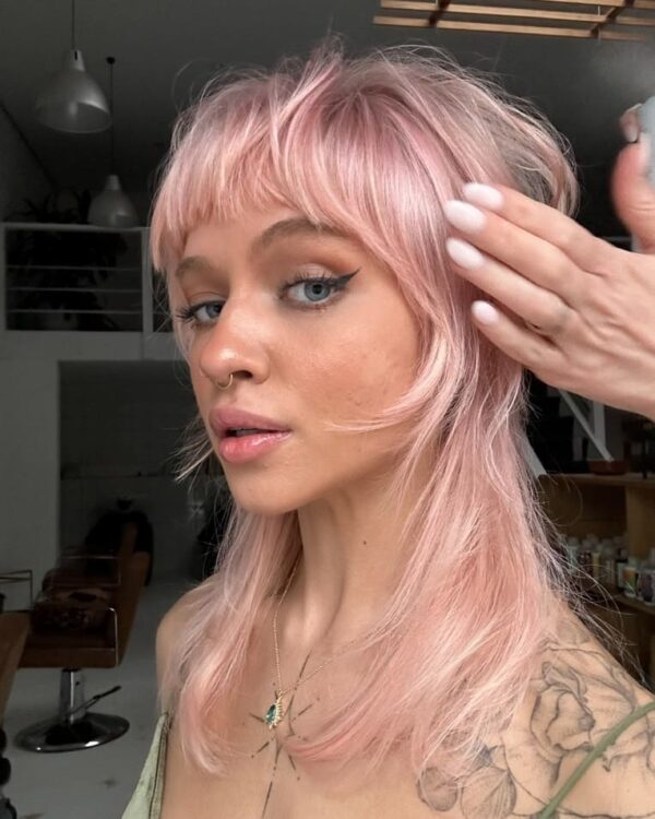 Shaggy, pastel pink mullet with textured bangs and layers.