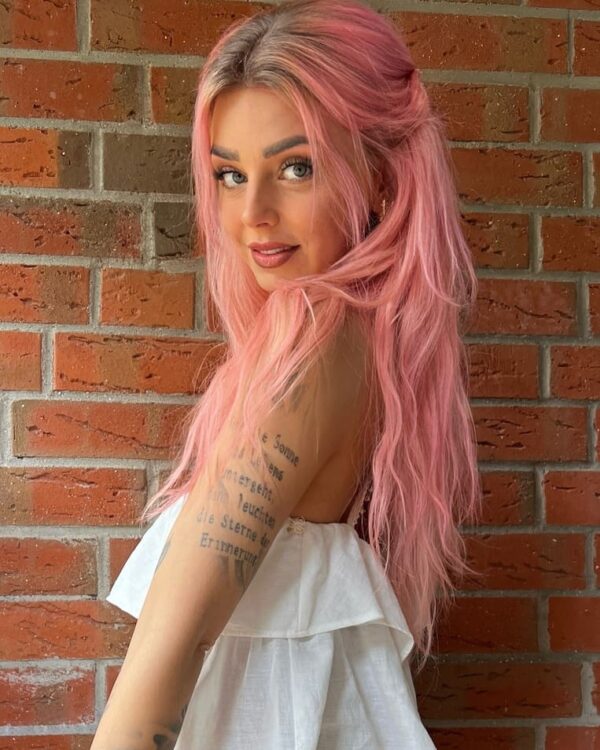 Soft rose pink hair styled in a relaxed half-up look.