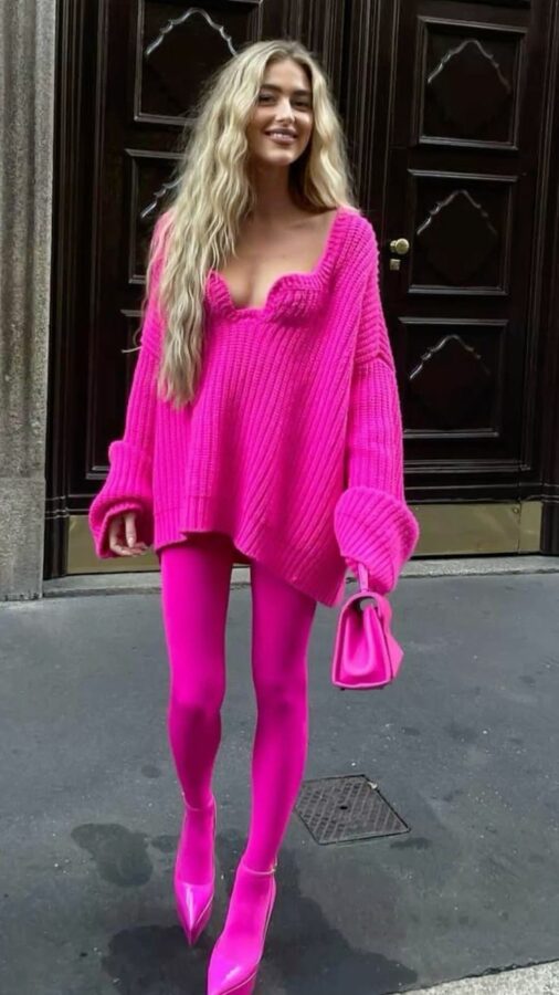 Woman wearing an oversized hot pink sweater, matching pink tights, pointed pink heels, and a mini pink handbag