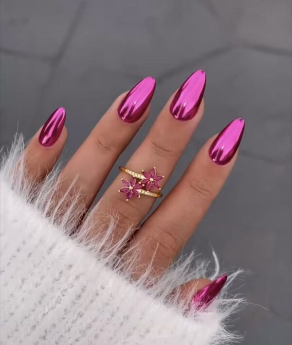 Hand with almond-shaped, hot pink chrome nails paired with a gold and pink floral ring