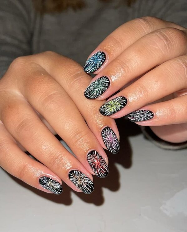 Black oval nails with sparkling multi-color firework designs bursting across each fingertip.