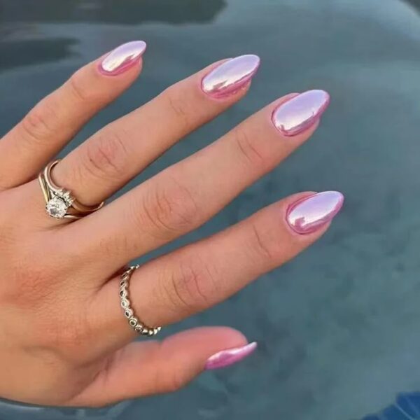 A hand with almond-shaped nails painted in a shiny iridescent pink chrome finish, perfect for summer.