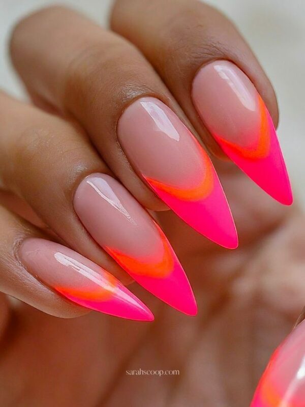 Stiletto nails with glossy nude bases and hot pink and orange flame-inspired French tips.