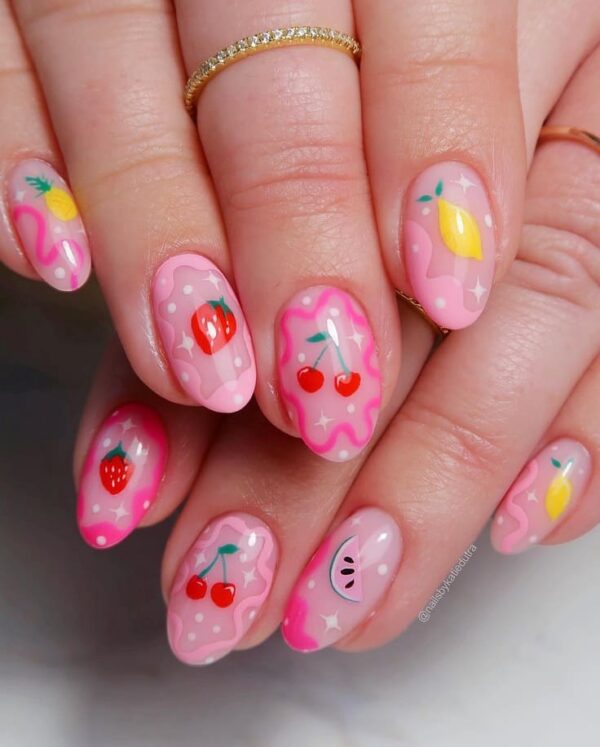 Playful pink nail design featuring hand-painted fruits like cherries, lemons, strawberries, and watermelons with a whimsical wavy background.