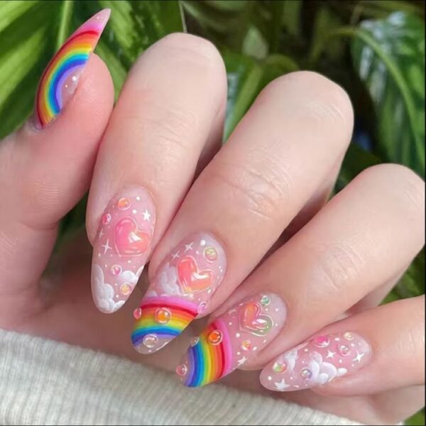 Almond nails with 3D hearts, rainbows, clouds, stars, and bubble-like accents on a soft pink base.
