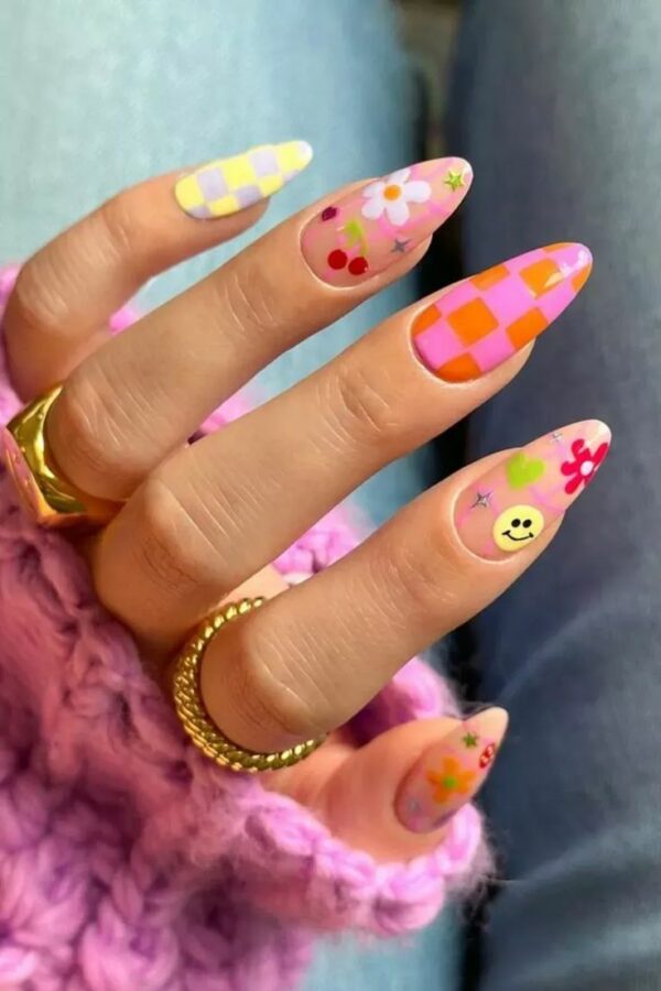 Long almond nails with pastel checkers, smiley faces, florals, cherries, and heart decals.
