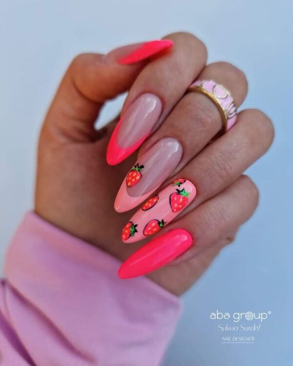 Hand with long almond-shaped nails featuring hot pink tips, glossy finish, and strawberry designs on accent nails.
