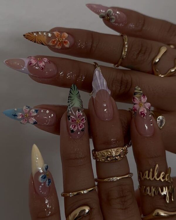 Long stiletto nails featuring colorful tropical flowers, palm leaves, animal prints, and 3D textures for a luxe island vibe.