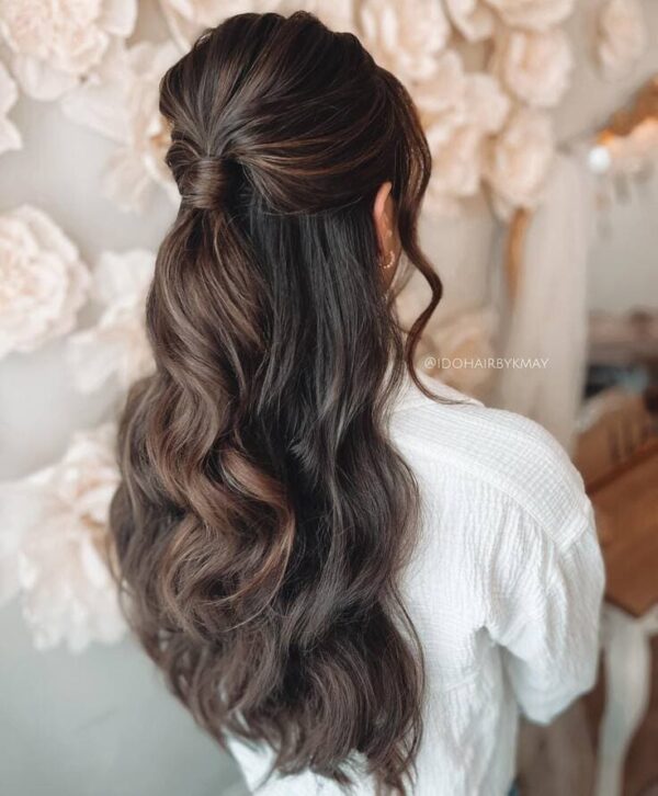 Long wavy brunette hair styled in a half-up ponytail with twisted detail