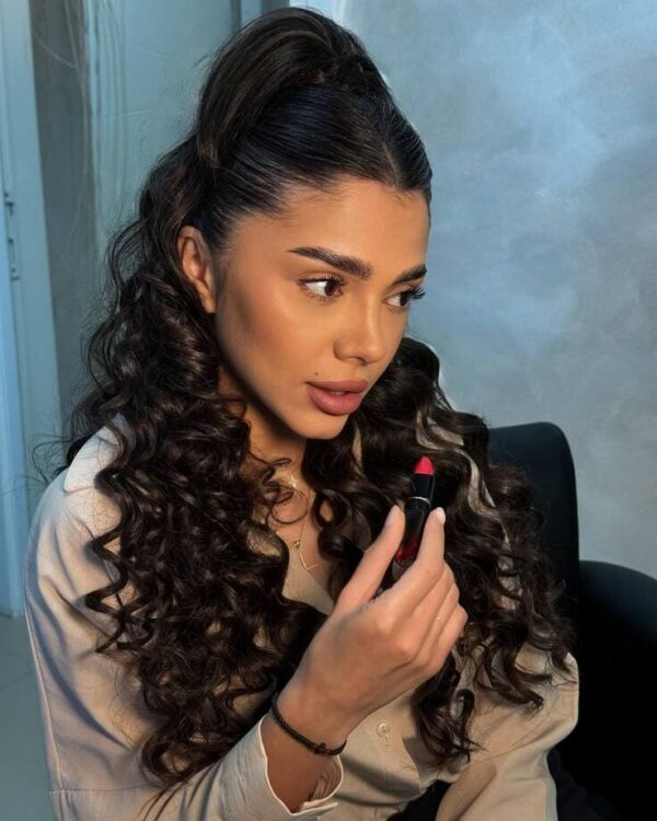 Long, dark spiral curls styled in a sleek high ponytail