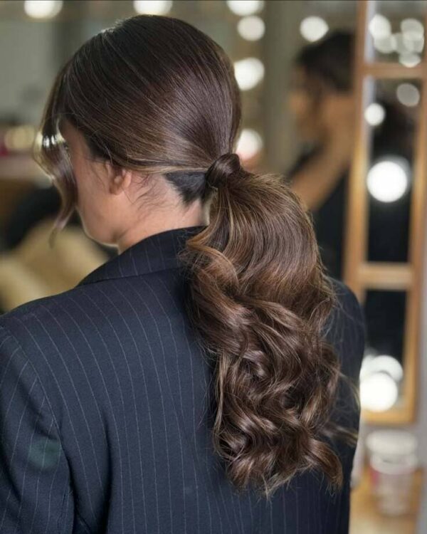 Sleek low ponytail with curled ends and hair-wrapped tie