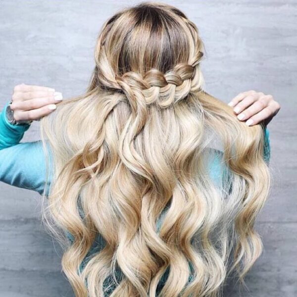 Long blonde wavy hair styled with a waterfall braid across the back