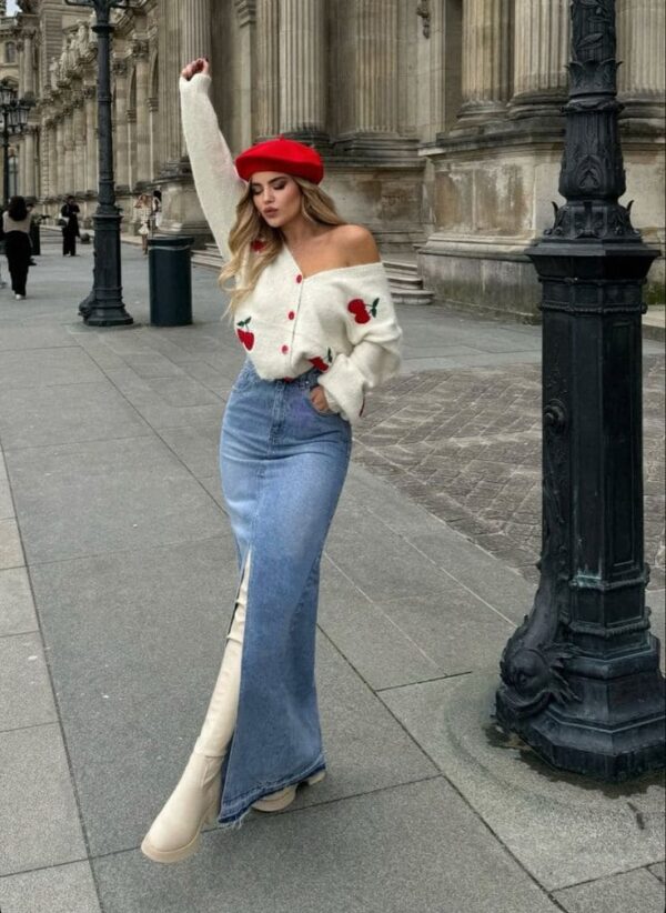 Woman wearing red beret, off-shoulder cherry sweater, and denim maxi skirt with cream boots