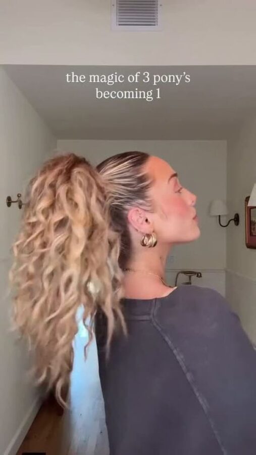 Long wavy high ponytail hairstyle with a sleek crown, soft curls, and a full ponytail created with a layered ponytail technique