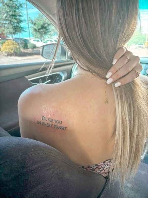 Small fine-line quote tattoo reading &ldquo;I&rsquo;ll see you in every sunset&rdquo; placed across the back of the shoulder